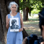 imagen de dos mujeres sosteniendo fotografías de personas en blanco y negro