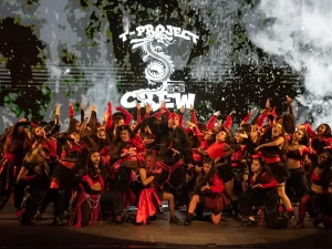 imagen de elenco de danza sobre el escenario vestido con trajes negros y rojo